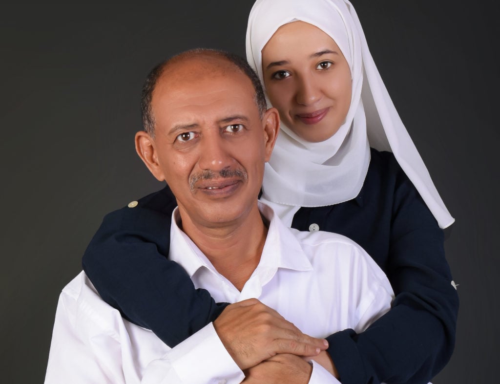 daughter embracing her father smiling and looking into the camera