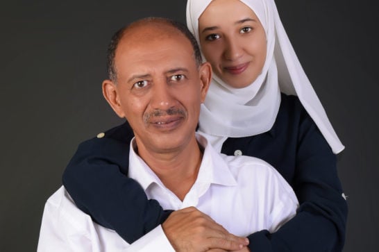 daughter embracing her father smiling and looking into the camera