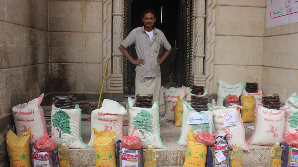 a man standing behind bags of sugar and other food items