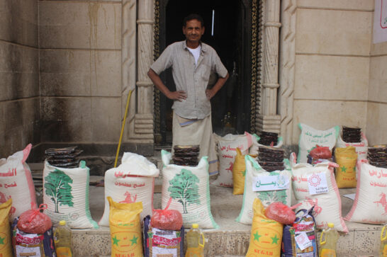 a man standing behind bags of sugar and other food items