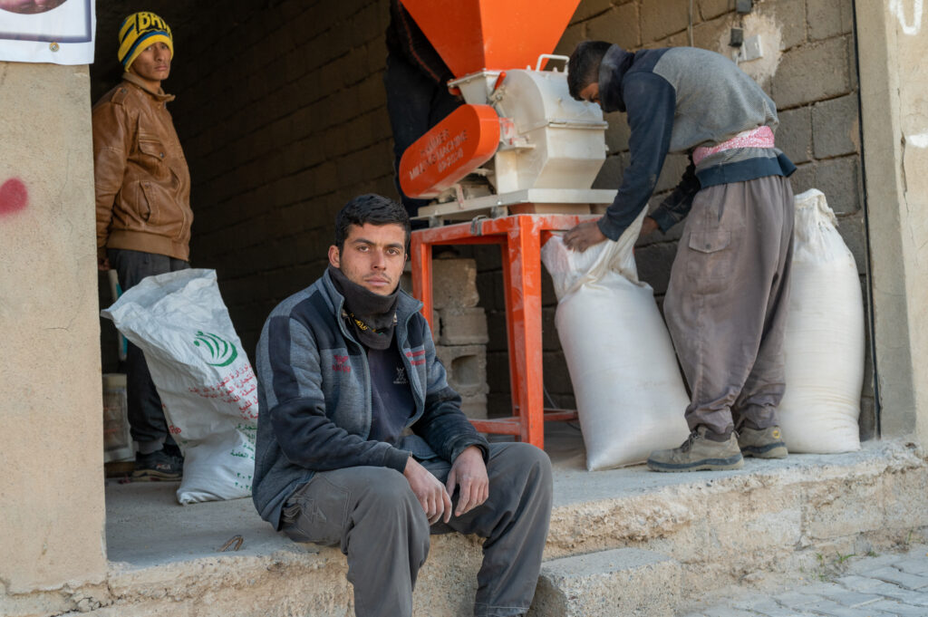 three men bags of flour grinder