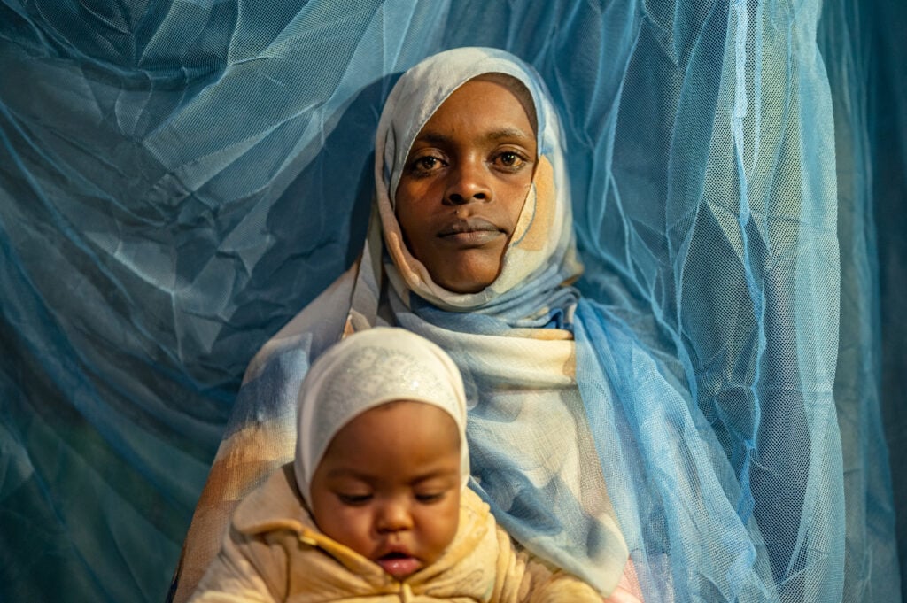 Sutume Aba Jihad with her 2-month-old daughter, Anisa, under a malaria net that protects their family from deadly malaria.