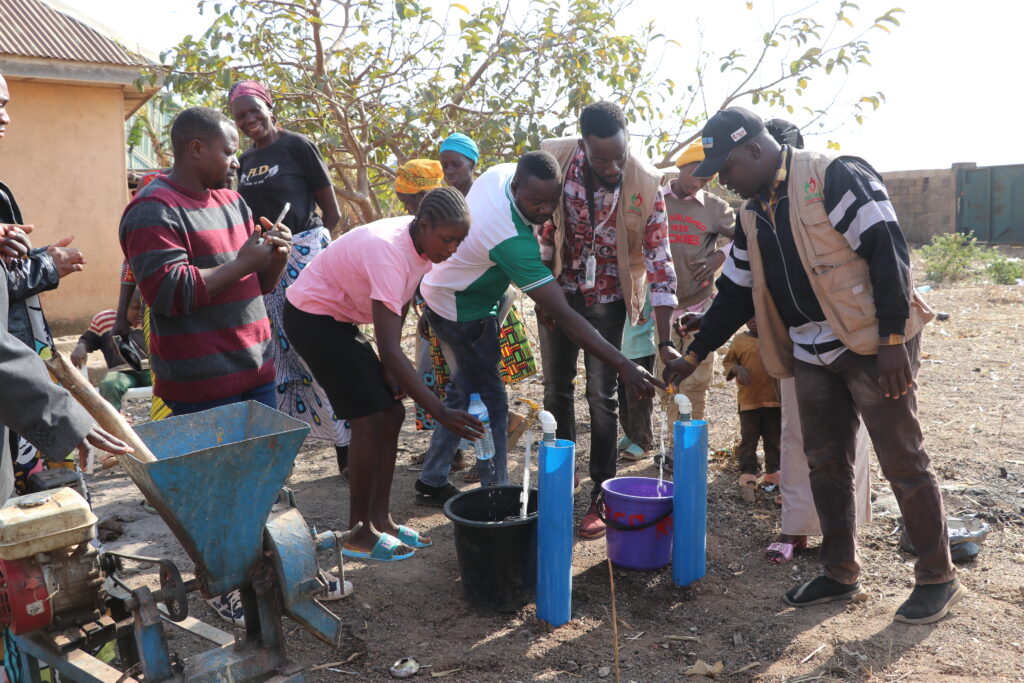 Nigerian humanitarian workers and displaced people around a water supply.