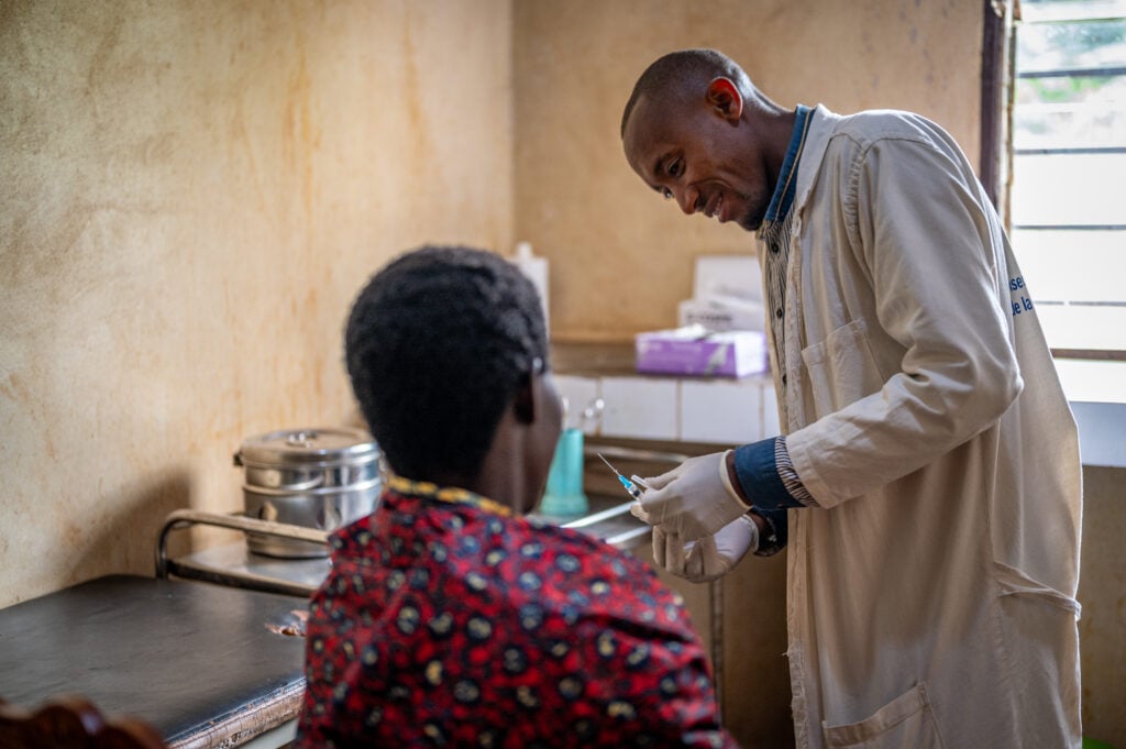 doctor holding a syringe and patient inside a health clinic