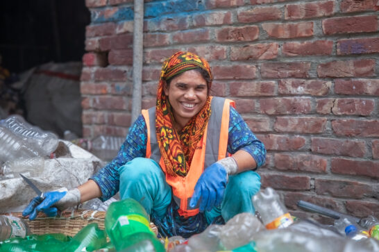 women sitting amid plastic bottles