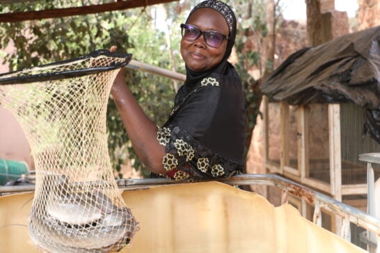 woman smiling and looking into the camera holding a fish funnel filled with fish