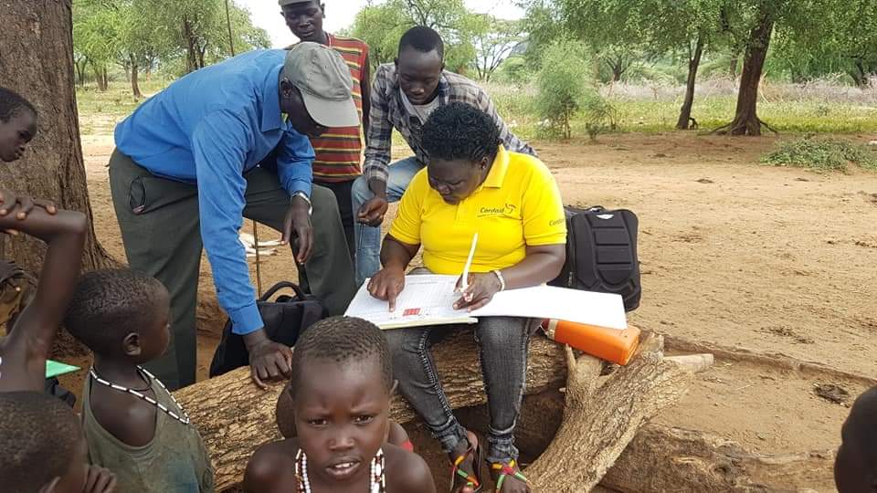 woman aid worker during field trip surrounded by men and children