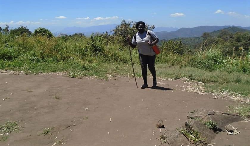 woman with walking stick and shoulder bag in the mountains