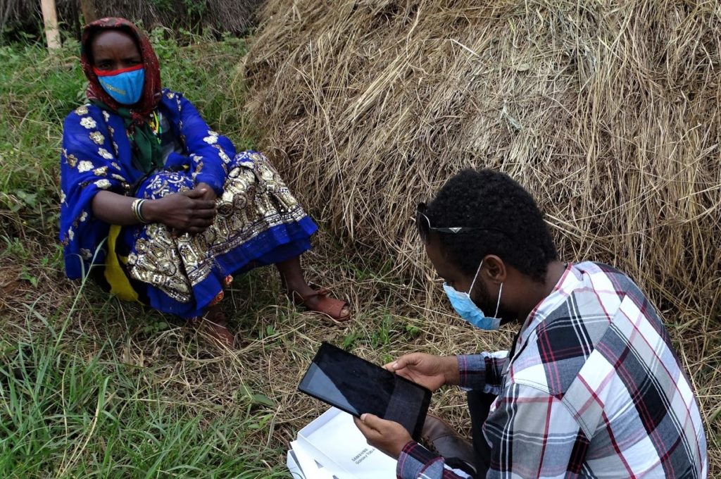 Yabello, Ethiopia, June 2020. A man, seated, conducts a digital rapid needs assessment asking questions to a woman and storing data on his tablet. Image: Cordaid