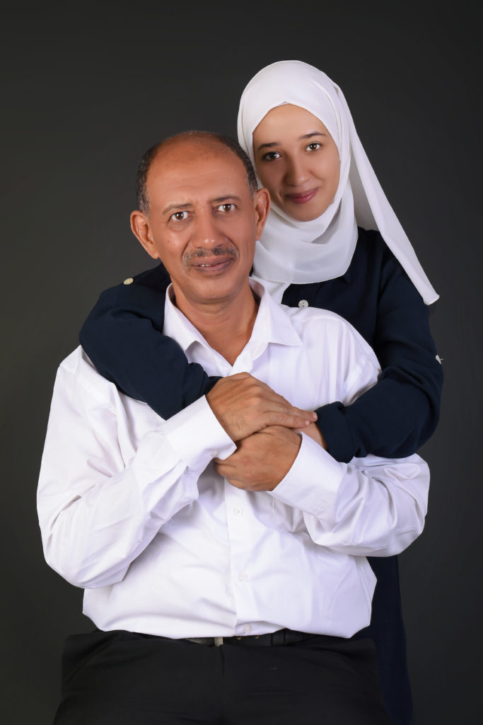 a daughter embracing her father in a photo studio setting