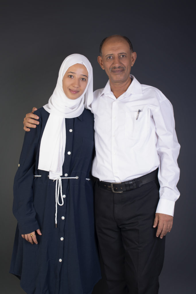 daughter and father standing next to one another in a photo studio setting