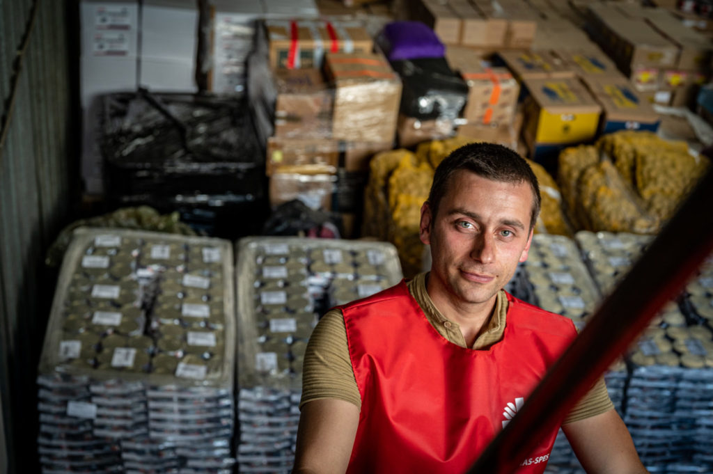 young man looking into the camera inside a warehouse with aid items