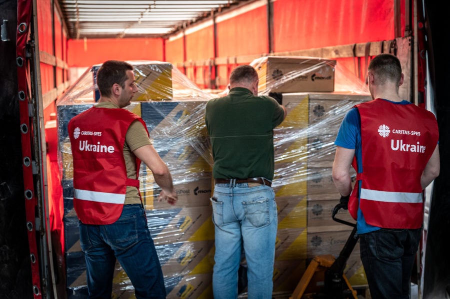 three men seen from the back unloading a truck