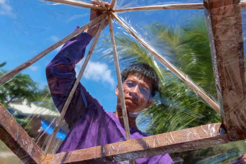 farmer holding a wooden construction with plastic foil