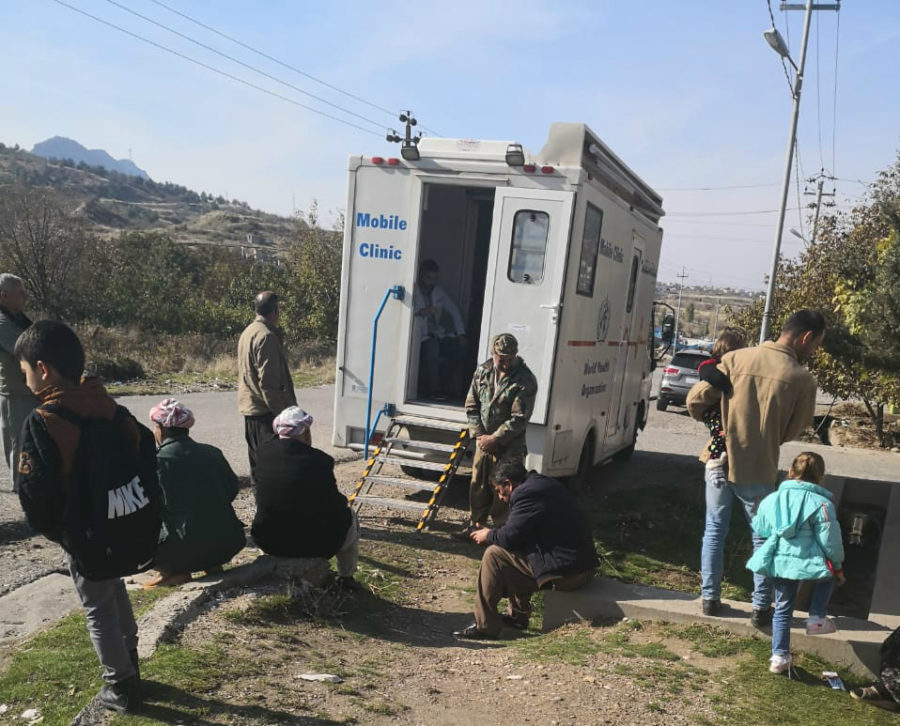 People sit outside the mobile clinic