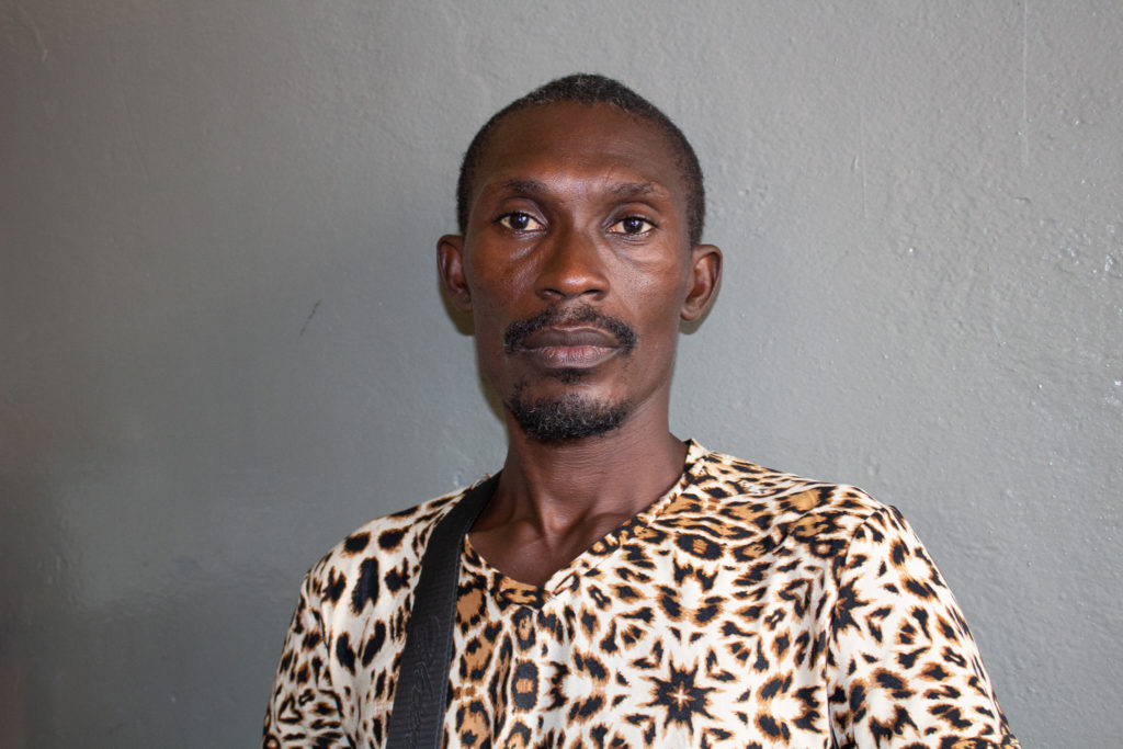 man looks into the camera with an intense look and serious expression wearing a shirt with animal print