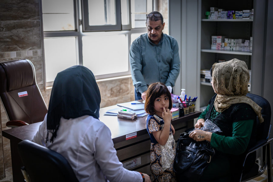 Dr. Muhazim Muhammed with a patient, her child and a Cordaid social worker in a consultation room in Sinjar hospital
