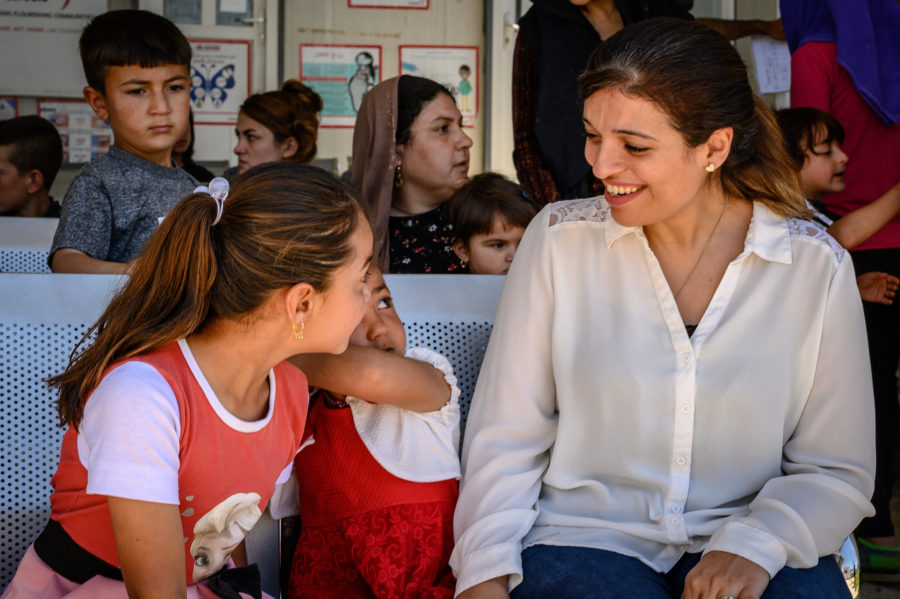 Dr. Tahireh Sadiq smiling as she chats with two girls on a bench