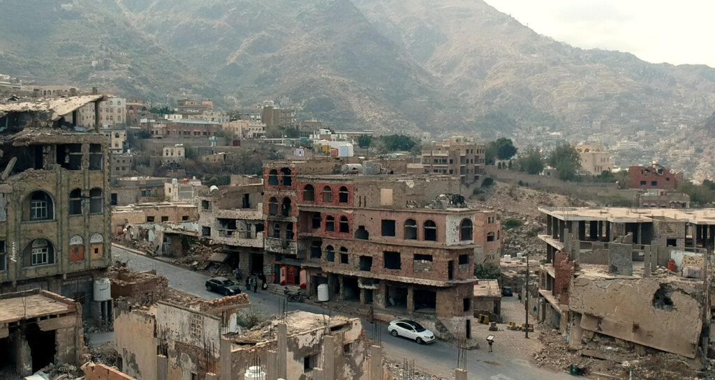 view of a city damaged and partly in ruins with mountains in the background