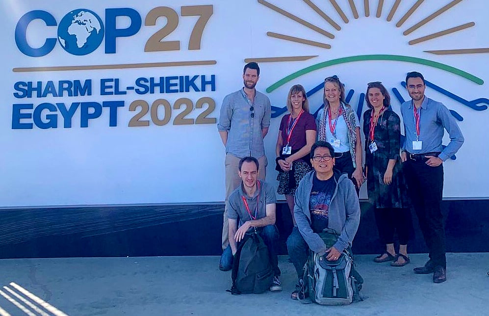 a group of men and women in fron of the climate summit banner in Egypt